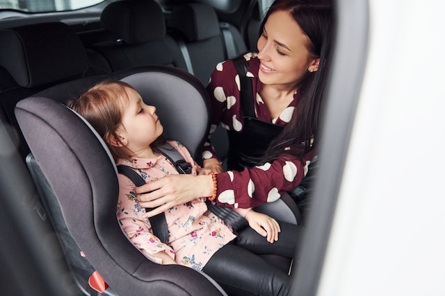 mom putting toddler in car