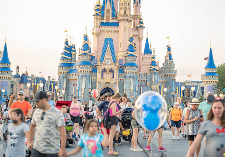 families walking down main street in disney world with the magic kingdom castle in the background